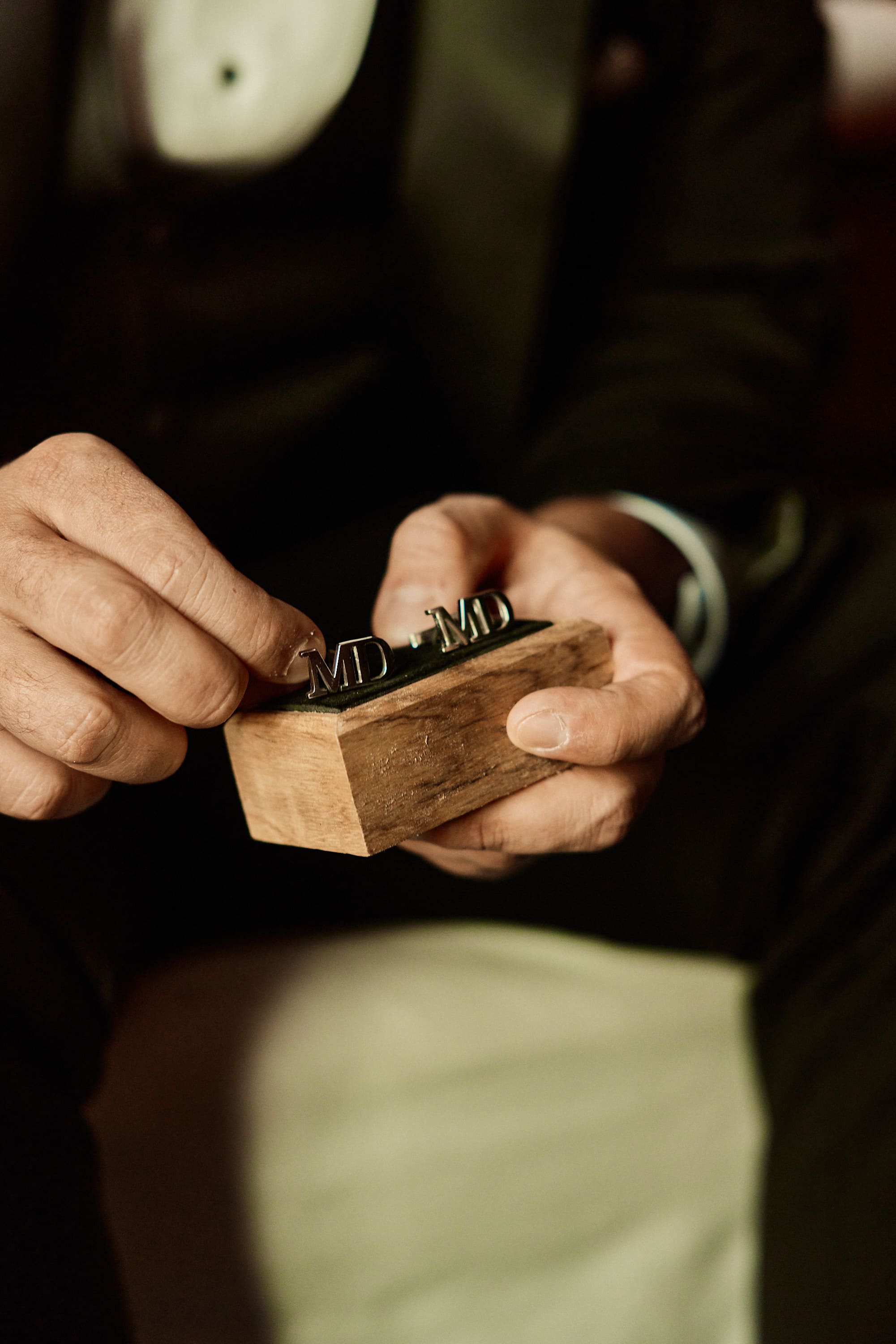 Detail shot of a groom handling a wooden ring box